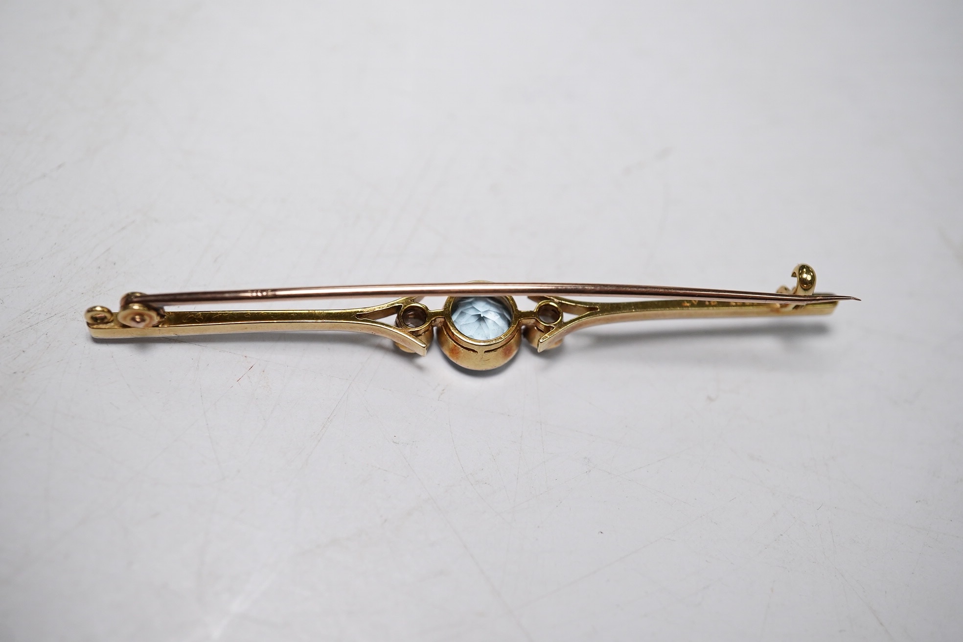 An Edwardian 15ct and plat. aquamarine and diamond set three stone bar brooch, 61mm, gross weight 3.9 grams. Condition - fair to good